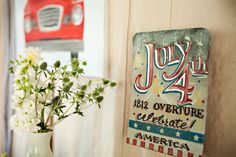 a vase filled with white flowers next to a red and white truck on the wall