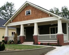 a small house with two porches and pillars on the front lawn, along with a red stop sign