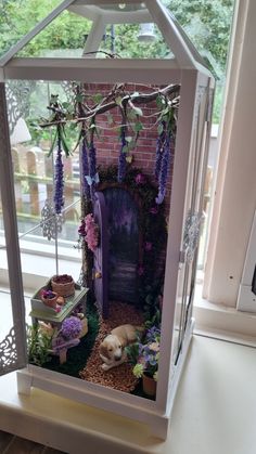 a doll house with a dog in it and flowers on the window sill above