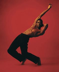 a man in black pants and no shirt is doing a dance move against a red background