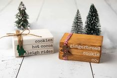 two small wooden boxes sitting next to each other with christmas trees in the background and gingerbread cookies written on them