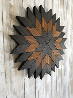 a wooden wall hanging on the side of a white wood planked wall with an abstract design