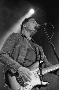 a man with a guitar standing in front of a microphone