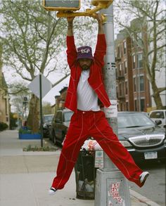 a man in red pants hanging from a street light pole