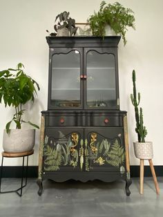 a black painted cabinet with plants on top