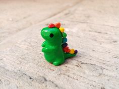 a small green toy dinosaur sitting on the ground