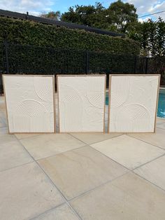 three white tile panels sitting next to a swimming pool