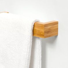 a white towel hanging on the wall next to a wooden holder with a bamboo handle