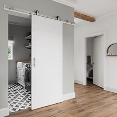 White barn door in a modern home leading into a laundry room with black and white tile Modern Barn Doors, Sliding Mechanism, Modern Barn Door, Open Concept Layout