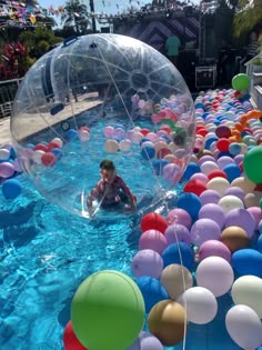 a person in a pool with balloons floating around