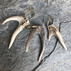 three deer antler's horns hang from hooks on a rock