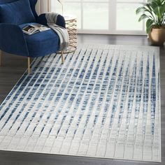 a blue and white rug in a living room next to a chair with a potted plant