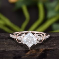 an engagement ring with a princess cut diamond in the center on top of a piece of wood