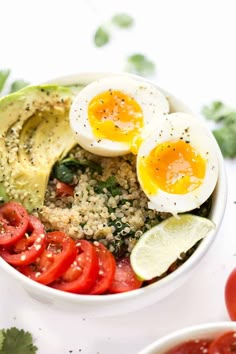 a bowl filled with vegetables and eggs on top of rice next to tomatoes, avocado