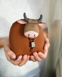 a person holding a cow shaped coin purse with a keychain in their hands