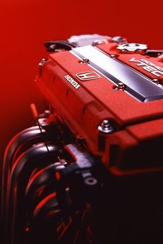 the engine compartment of a red car is shown in this artistic photo, with its hood up