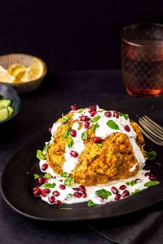 a black plate topped with food and garnished with pomegranates