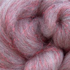 a close up view of a skein of gray and pink yarn with red streaks