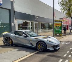 a silver sports car is parked on the side of the road in front of a store