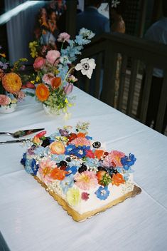 there is a cake on the table with flowers in vases next to it,