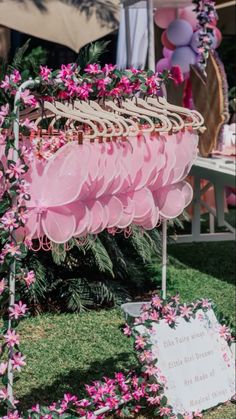 a bunch of pink flowers are hanging from a rack in the grass near a sign