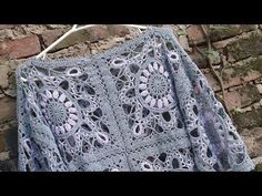 a blue crocheted shawl hanging on a brick wall