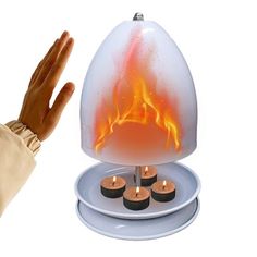 a person holding their hand up in front of a lit candle holder