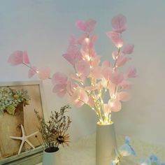 two vases with flowers in them sitting on a table next to a starfish