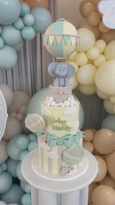 there is a cake with an elephant on top and balloons in the background for decoration