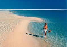 a man walking on the beach in shallow water