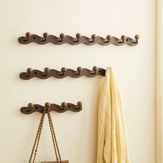 the coat rack is hanging on the wall next to a purse and towel hooks