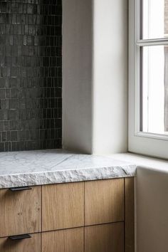 a kitchen counter with marble top next to a window