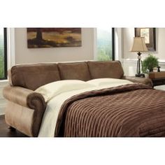 a bed sitting next to a brown couch in a bedroom