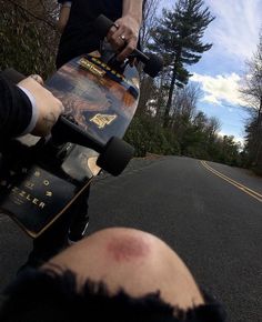 a man riding a skateboard down the middle of a road next to another person