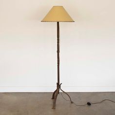 a floor lamp with a yellow shade on it's side and a cord attached to the base