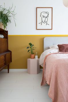 a bed room with a neatly made bed and a potted plant