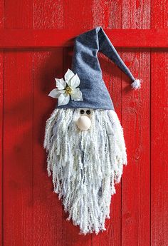 a gnome's head hanging on the side of a red door with white flowers