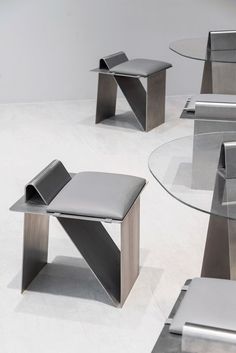 three modern tables and chairs are arranged in the middle of a white floored room