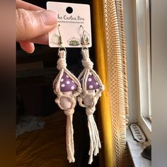 a pair of purple and white earrings with polka dots on them hanging from a hook