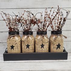 four jars with branches and stars painted on them