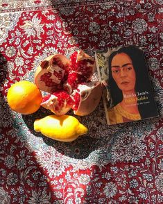 a table topped with fruit and books on top of a red cloth covered tablecloth