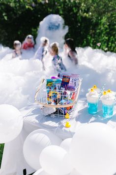 a basket filled with books sitting on top of a table covered in white balloons and streamers