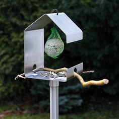 a bird feeder with a green bag hanging from it's side