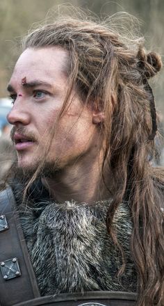 a close up of a person with long hair wearing a fur collar and leather armor