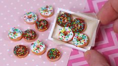 a box filled with lots of donuts covered in sprinkles on top of a table