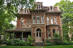 an old brick house in the middle of some trees and grass with stairs leading up to it