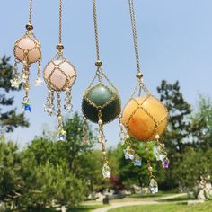 three different colored balls hanging from chains in the air with trees and grass behind them