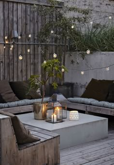 an outdoor living area with couches, tables and lights