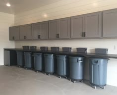 a row of trash cans sitting on top of a counter in a room filled with cabinets