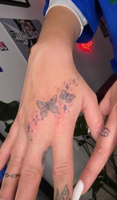 a person's hand with two butterflies tattooed on the middle of their left hand